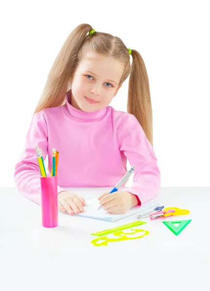 Litli girl sitting at table and writing with ballpoint pen — Stock Photo, Image