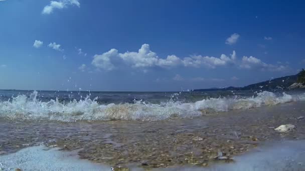 Kalm vriendelijke kleine golven op schoon kleine stenen strand onder de blauwe hemel — Stockvideo