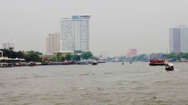 BANGKOK, THAILAND - APR 12: Boats and ships on wide fast Chao Phraya river with high buildings on the river banks on Apr 12, 2013 in Bangkok, Thailand. — Stock Video