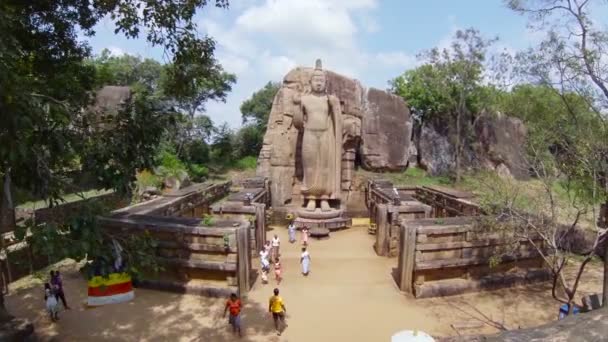 KEKIRAWA, SRI LANKA - APR 16: Peregrinos rezam perto da estátua de Buda de Avukana em 16 de abril de 2013 em Avukana, Sri Lanka. É 40 pés (12 m) estátua de pé elevada esculpida fora da rocha de granito no 5o século . — Vídeo de Stock