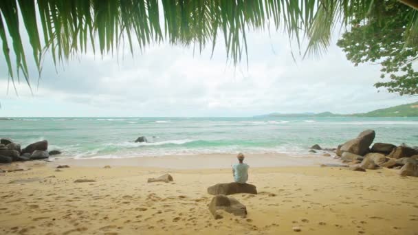 Video 1920x1080 - A lone man sits on the shore of a tropical ocean — Stock Video