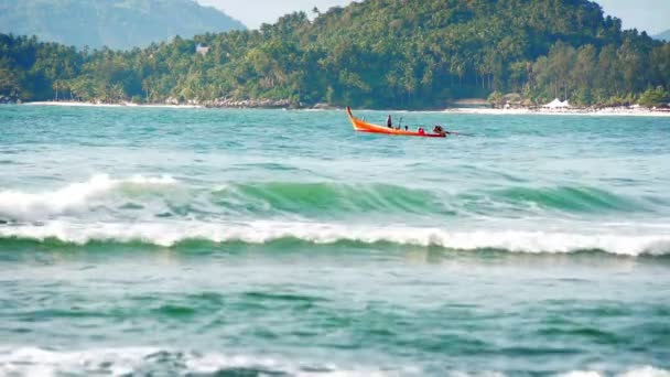 PHUKET, THAILAND - SEP 13: People in traditional wooden long boat navigate in blue waves on Sep 13, 2013 in Phuket, Thailand. — Stock Video