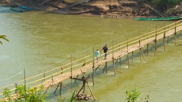 LUANG PRABANG, LAOS - 08 DEC 2013: Unidentified people move along bamboo bridge above river — Stock Video