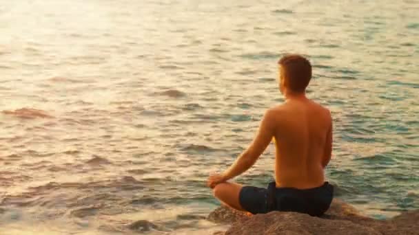 Видео 1920x1080 - Молодой человек, практикующий йогу на берегу океана — стоковое видео