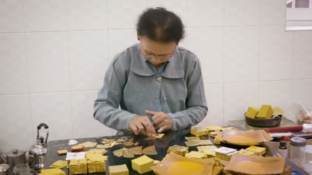 MANDALAY, MYANMAR - 13 ENE 2014: Producción de hojas de oro mediante la creación de la misma pieza de una hoja extremadamente delgada para su uso en el dorado . — Vídeo de stock