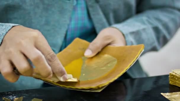 MANDALAY, MYANMAR - 13 ENE 2014: Producción de hojas de oro mediante la creación de la misma pieza de una hoja ininterrumpida extremadamente delgada para su uso en el dorado. De cerca. . — Vídeo de stock