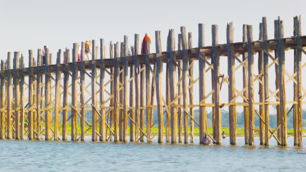 MANDALAY, MYANMAR - 13 JAN 2014: U Bein Bridge across the Taungthaman Lake. The 1.2 km  bridge was built around 1850 and is the oldest and longest teakwood bridge in the world — Stock Video