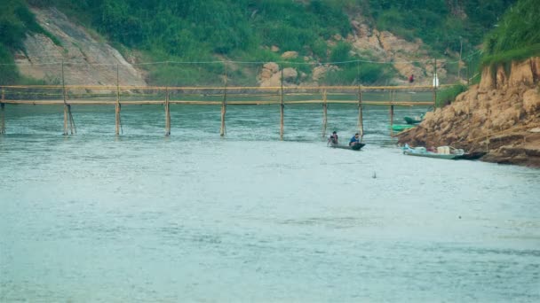 Luang prabang, laos - circa dec 2013: små båtar lätt passera under en bambu bron — Stockvideo