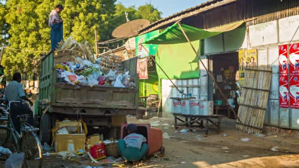 BAGAN, MYANMAR - 11 JAN 2014: Workers on garbage truck collect garbage from a durty street — Stock Video