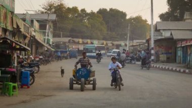 Bagan, myanmar - 11 Ocak 2014: yaygın Asya Birmanya tozlu yol bir sokak arabalar su taşıma sepeti ve Motosiklet ile ulaşım trafik ile.