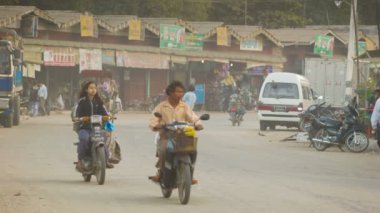 BAGAN, MYANMAR - 11 JAN 2014: Horse carriages on common Asian Burmese dusty road and transport traffic on a street with cars, motorbikes and bicycles.