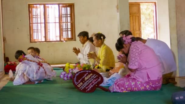 BAGAN, MYANMAR - 12 มกราคม 2014: พิธีเปิดใหม่ของพม่า Shinbyu เป็นประเพณีของพุทธศาสนาเทรวาดาซึ่งหมายถึงการเฉลิมฉลองที่ทําเครื่องหมายตามธรรมเนียมของพระสงฆ์ของเด็กชาย พิธีกรรมในห้อง — วีดีโอสต็อก