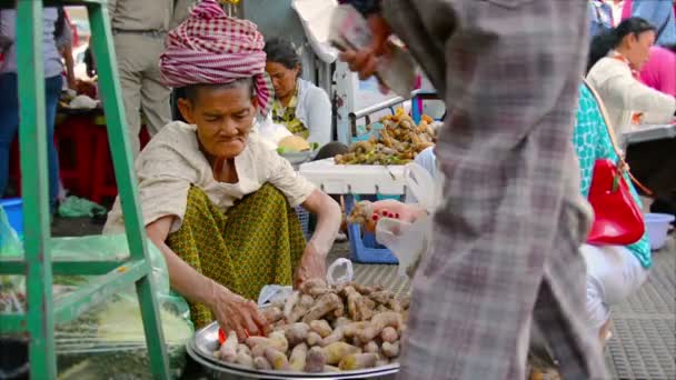 PHNOM PENH, CAMBODIA - 29 DEC 2013: The old lady selling sweet potatoes on the market — Stock Video