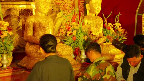 БАГАН, МИАНМАР - CIRCA JAN 2014: Посетители буддийского храма покрыли статуи Будды золотыми листочками — стоковое видео