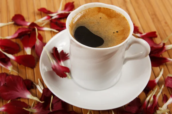 Xícara de café com pétalas na mesa — Fotografia de Stock