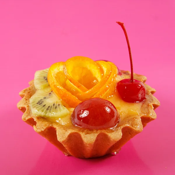 Sweet cake with fruits on pink background — Stock Photo, Image