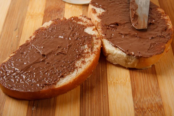 Roti dengan coklat menyebar di atas meja — Stok Foto