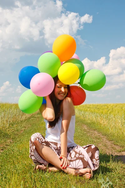 Gelukkig jonge vrouw en kleurrijke ballonnen — Stockfoto