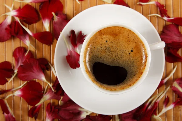 Koffiekopje met bloemblaadjes op tafel — Stockfoto