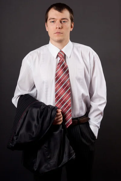 Guapo joven hombre de negocios de pie sobre fondo negro — Foto de Stock