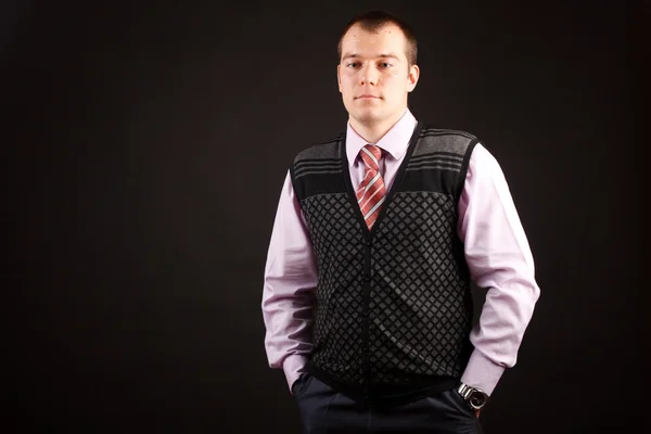 Schöner junger Geschäftsmann steht auf schwarzem Hintergrund — Stockfoto