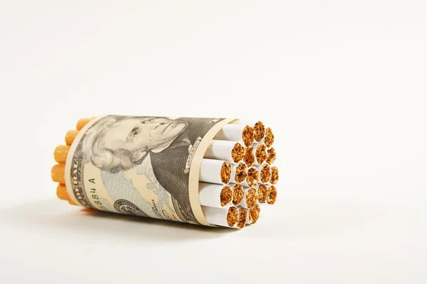 Cigarrillos y dinero sobre un fondo blanco . — Foto de Stock