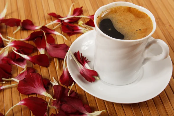 Coffee cup with petals on table Stock Photo
