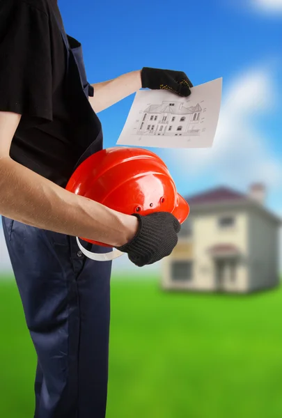 Construction hard hat and blueprint in hands — Stock Photo, Image