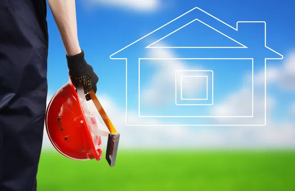 Construction hard hat in hand. House icon — Stock Photo, Image