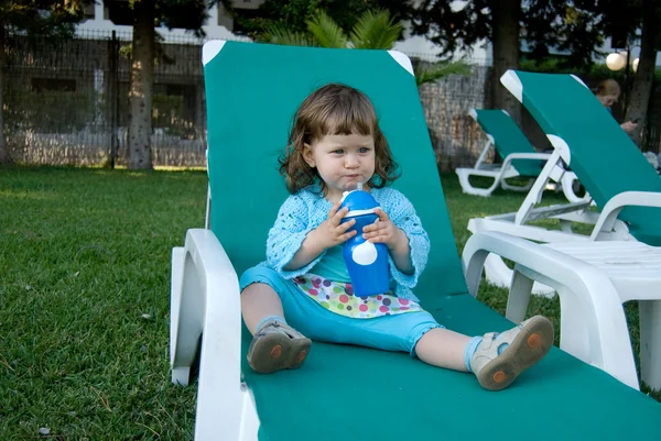 The baby girl drinks water in resort — Stock Photo, Image