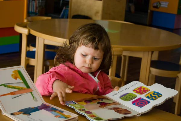 La niña está buscando libro. —  Fotos de Stock