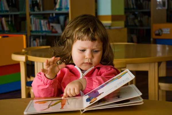 A menina está procurando livro — Fotografia de Stock