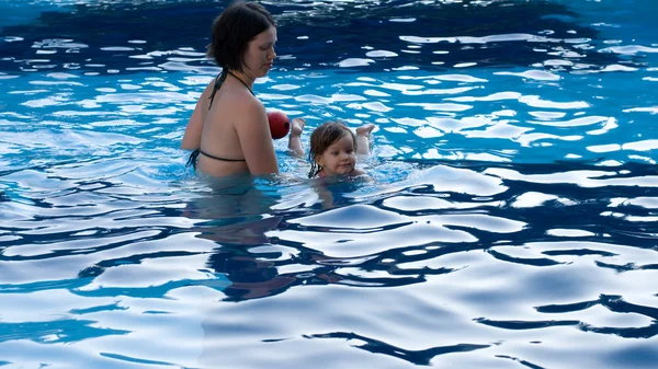 A menina brinca com sua mãe na piscina — Fotografia de Stock