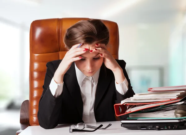 Angespannte junge Geschäftsfrau hält ihren Kopf bei der Arbeit — Stockfoto