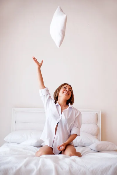 Mulher loira se alongando e sorrindo na cama pela manhã no quarto em casa — Fotografia de Stock