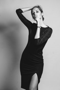 Stüdyoda zarif bir elbiseyle poz veren güzel bir kadın.