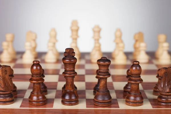 Placa de xadrez com figuras em preto e branco sobre fundo cinza — Fotografia de Stock