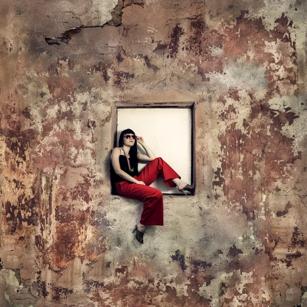 Girl sitting on window of an abandoned building — Stockfoto