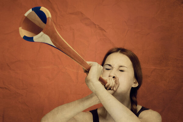 Young girl blowing the trumpet over red background retro stylize