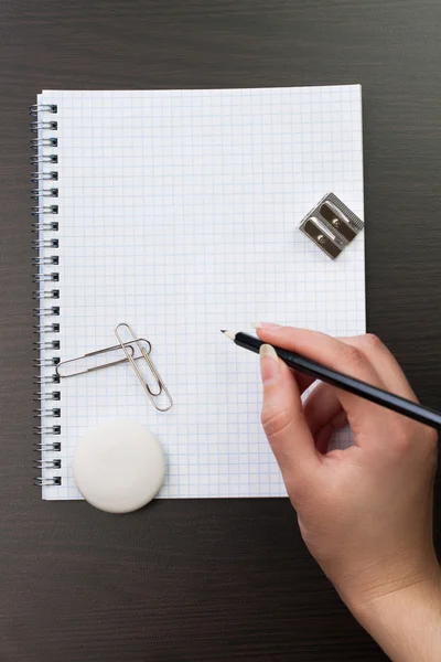 Frau schreibt im Büro mit Bleistift auf Notizbuch — Stockfoto