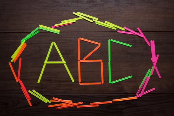 Abc letters formed with counting sticks over wooden background — Stock Photo, Image