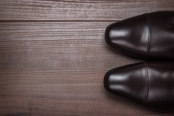 Kahverengi ayakkabılı bir adam tahta zeminde duruyor.