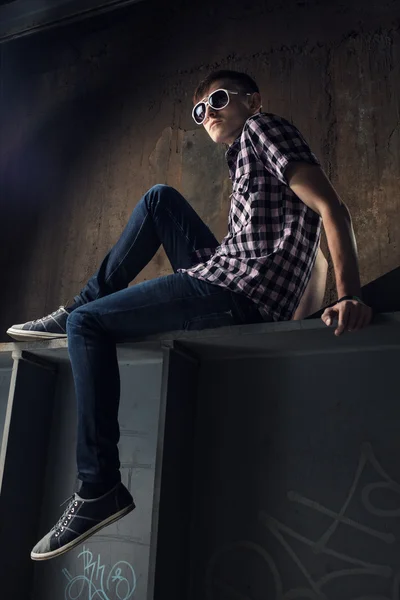 Young man sitting over industrial background — Stock Photo, Image