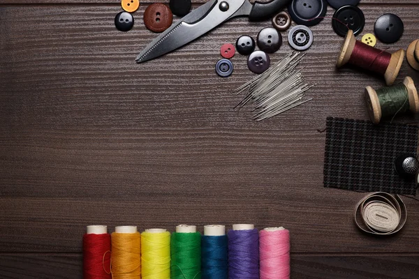 Boutons, aiguilles et fils multicolores sur table en bois — Photo