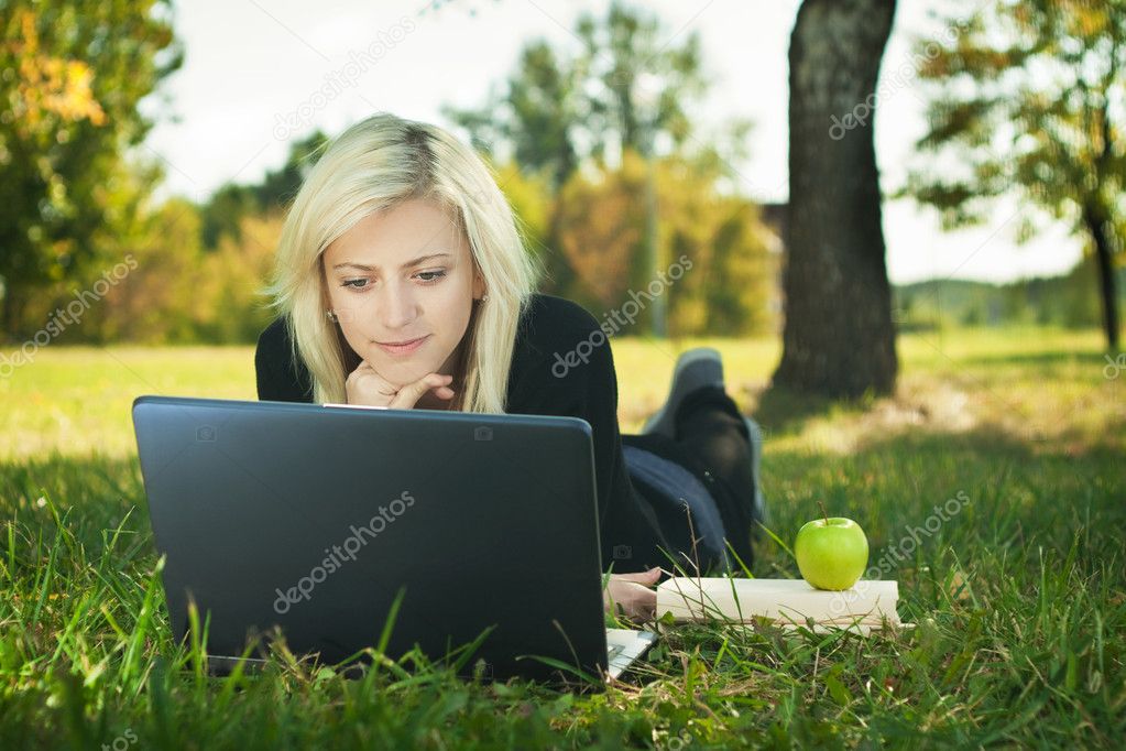 Student girl with laptop studying in park