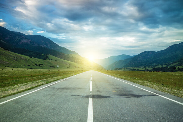 Road in summer mountains to the sunset