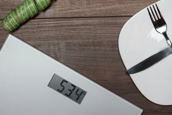 Dieting concept with scales on wooden floor — Stock Photo, Image