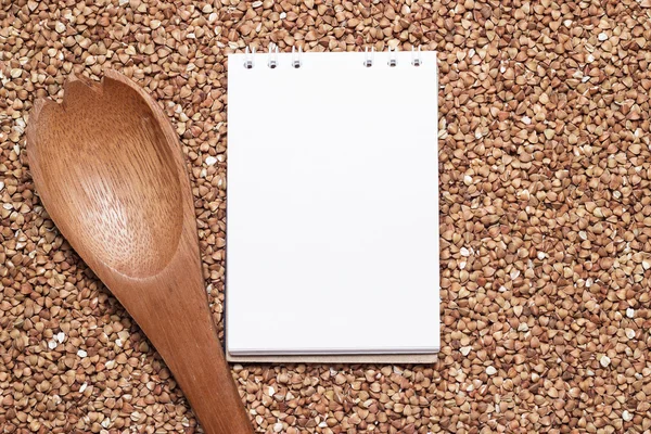 Kasza gryczana z brązowy drewnianą łyżką i notatnik — Zdjęcie stockowe
