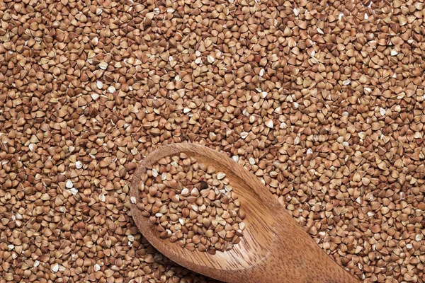 Buckwheat with brown wooden spoon — Stock Photo, Image