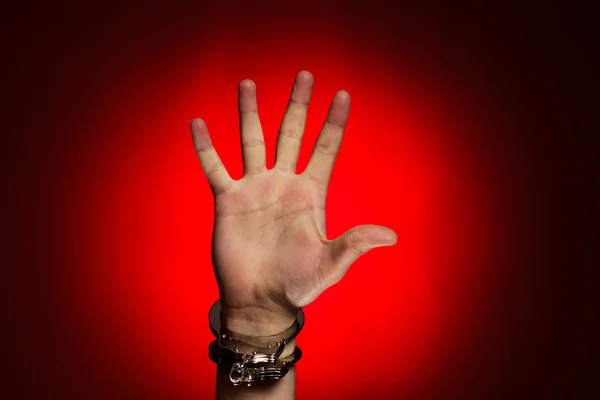 Руки в наручниках на красном фоне — стоковое фото